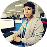 Man wearing headset sitting at a computer desk in an office.